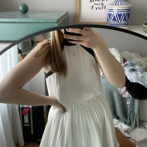 Urgullig blus med rosett i bak - Fantastiskt blus i svart och vit. Charmig halsringning med knytning i bak. Perfekt till kjol eller kostymbyxor. 