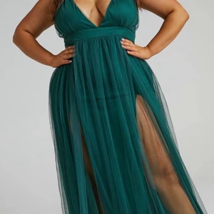 Lång mörkgrön balklänning med slits  - Endast prova balklänning med slits och korsad rygg. Mörkgrön/ emerald grön. Tyckte tyvärr inte om hur den satt på mig men väldigt fin färg och form. Bilder från hemsidan. Pga dyr tax och retur pris kunde jag inte skicka tillbaka så jag hoppas att den passar dig och är din dröm klänning! Köptes för 800kr och är i nyskick och oanvänd.