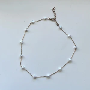 Halsband  - Halsband med vita pärlhjärtan.                                    Använt lite gran men inte så mycket, ganska bra skick, vet inte vart den är ifrån fick den i födelsedagspresent                                                     30kr + frakt 