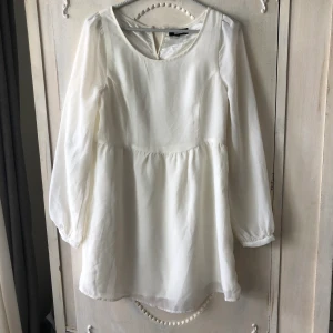 Kort vit studentklänning sommarklänning  - Kort vit sommarklänning tunika som passar perfekt till studenten. Två lager i kjolen och täckande typ upp till. Genomskinligt tyg på ärmarna. Från Bikbok strl Small
