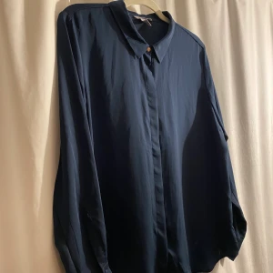 HM office skjorta i fint material plussize stl 46 - Fin skjorta i polyester med vackert fall. Guldknapp vid kragen, övriga knappar dolda. Normal i storleken. Nyskick och knappt använd.  Köparen betalar frakten.