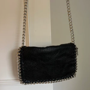 Väska från tiamo - Svart axelremsväska i skinnimitation från tiamo! Ett fack på insidan och ett på baksidan av väskan. Nypris 499, Knappt använd!! Köpare står för frakten alternativt kan tag mötas upp☺️