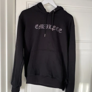 Hoodie - Svart hoodie med glittrande stenar från emplece. Nypris på tröjan är 899kr. 