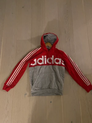 Adidas Hoodie - Säljer nu en röd adidas hoodie då den inte kommer till någon användning längre. Huvtröjan är i mycket fint skick och inga märken på användning. Tröjan är i storlek S Vid eventuella frågor eller funderingar är det bara att höra av sig! Kan samfrakta!