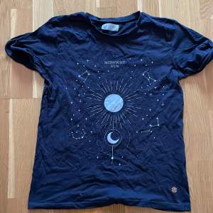 En svart T-shirt med små stenar på trycket som har med astronomi att göra 