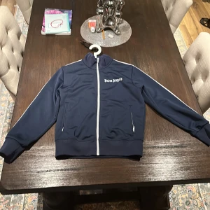 Palm angels mörkblå logo track jacket  - Säljer en knappt använd palm angels zip up hopdie den är i 10/10 skick och har bara använt den cirka 7 gånger. inköps pris var 4300 kr. Finns även kvitto