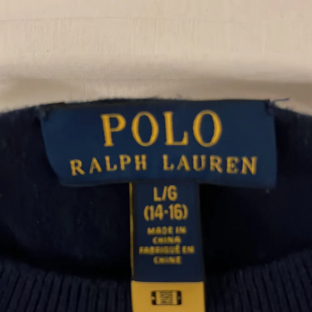 Det här är en Ralph lauren tröja i bra skick. Den är mörkblå och märket är rött.  Den har inga flaws och är i storlek 14-16 år. . Stickat.