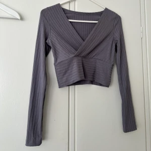 Lila tröja. - Lila aktig tunntröja med omlottringning.