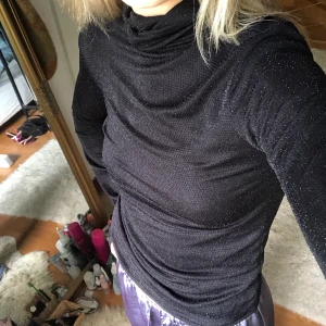 Polo tröja - En svart polo tröja som har små stenar vilket ger den en glittrande look. Står ingen storlek men skulle säga att den passar xs-s.