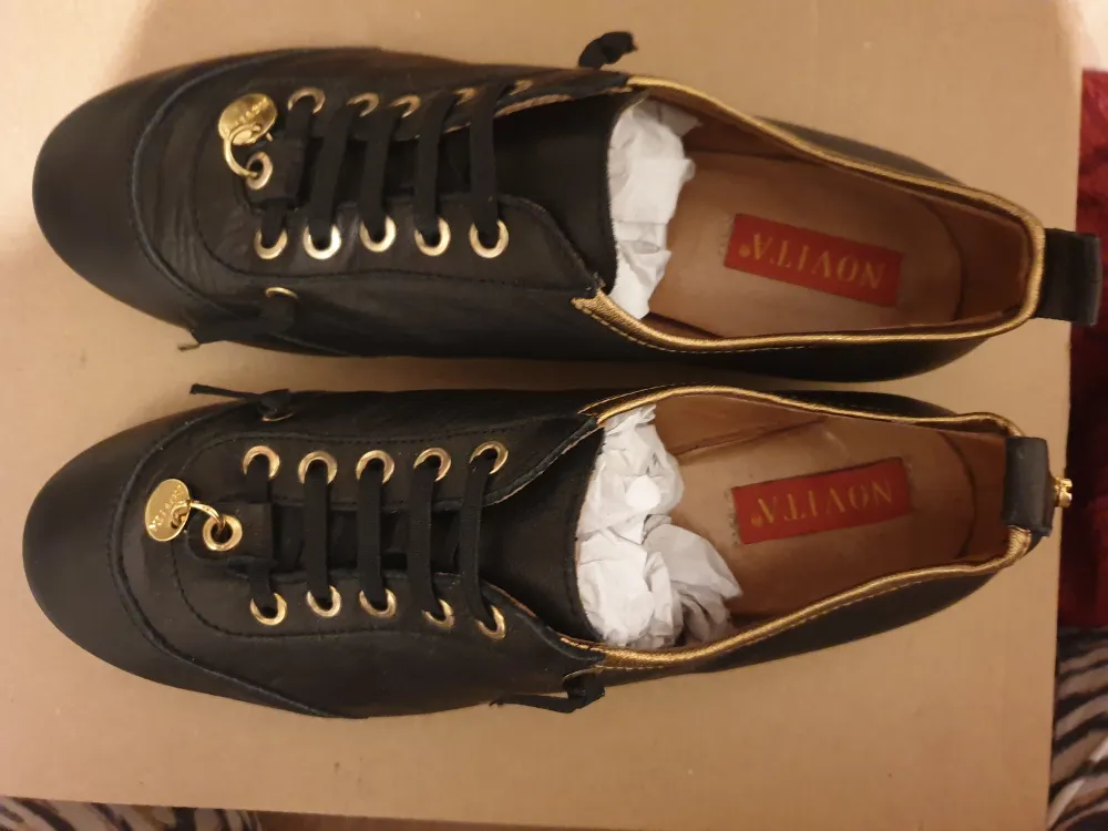 Snygga svarta skor med gulddetalier. Säljs billigt för att jag vill bli av med den. Skor.