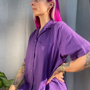 Oversized skjorta - • Mörk lila skjorta med textur i tyget, storlek XL • Två front fickor med dragkedja. Cool och snygg skjorta som kan stylats klassiskt med några snygga brallor, eller casual med ett par cykel shorts. Mäter 73cm från axel o ner.