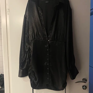 Svart klänning - Svart glansig klänning från Gina i strl 44 men den är mer som en 40-42 i underdelen och 44 i överdelen, snyggt om man vill ha pösigt. Använd 1 gng, 250kr inkl frakt