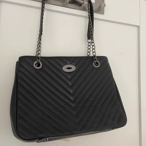 Svart väska stor - Väskan är använd några få gånger men råkat bli lite klämd i garderoben. Skicket i övrigt är väldigt bra. Väskan är köpt i en gullig affär i polen. Det finns 3 fack varav ett med dragkedja i mitten. Väldigt rymlig.