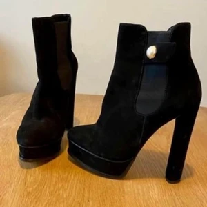 Nya Kurt Geiger platåpumps klackhöjd 13,5 - Supersnygga platåpumps design från Kurt Geiger. Guldknappar. Bekväma att gå i pga platå fram 4,5cm. Färg :svart Material: Mocka . Stl 36