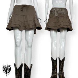 Minikjol - Khaki lågmidjad mini/midkjol från Million Dollar Babe, storlek 10. Örn med kristaller på baksidan, de flesta kristallerna är kvar. Några få fläckar som verkar inte försvinna. ⚠️MÅTT: Höftbredd 35cm & längd 36cm