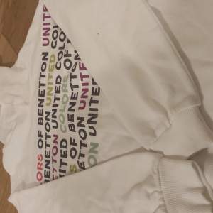 En vit hoodie med text i olika färger.