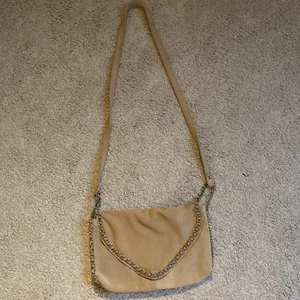 Väska  - En beige väska med silver färgad kedja 