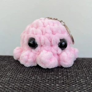 Virkad minibläckfisk-nyckelring - Egengjord, virkad minibläckfisk med nyckelring, i nyskick. Garnet är 100% polyester. Den är ca 6 cm lång och 5 cm hög. Den kostar 39kr totalt med frakt!