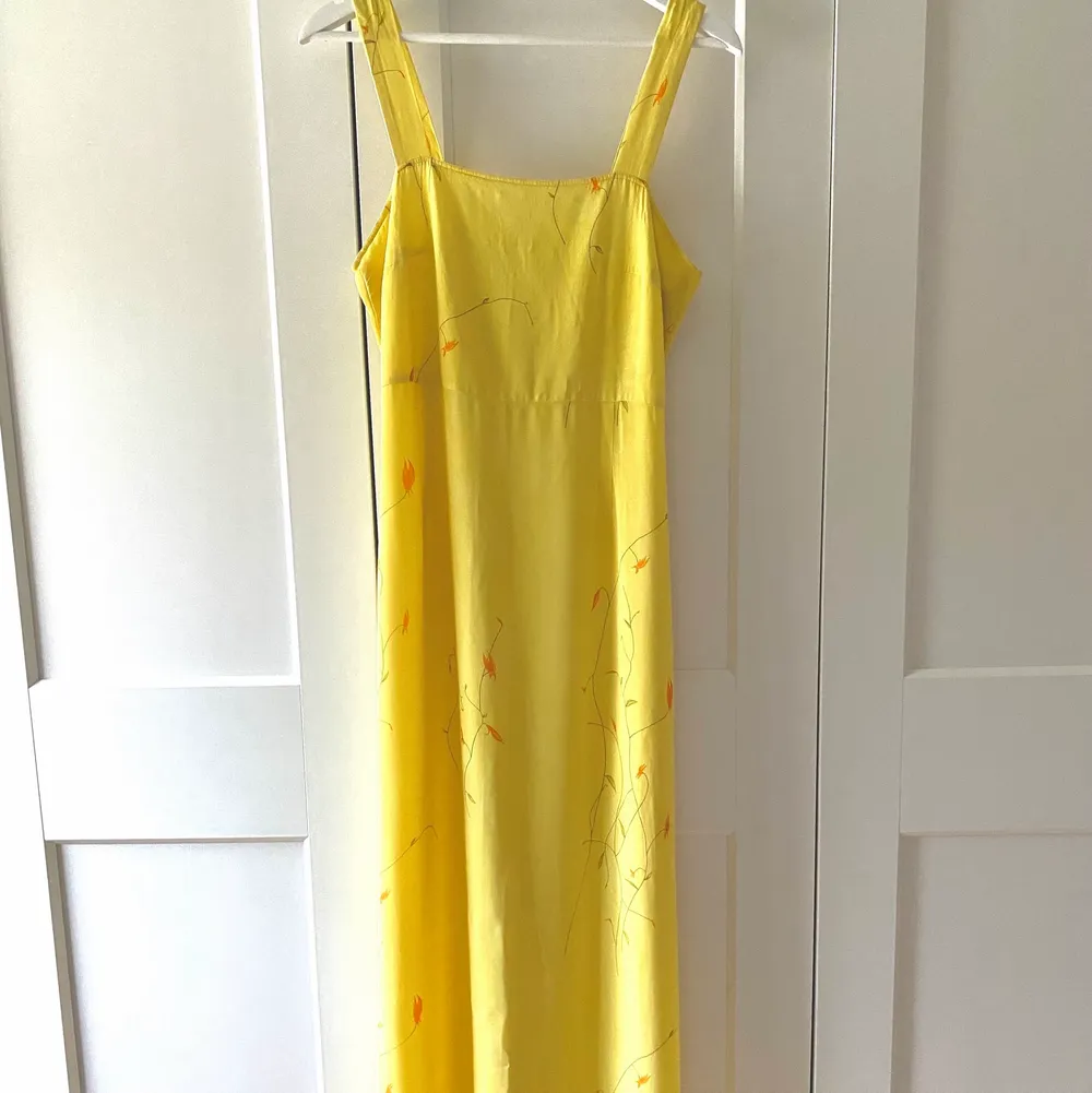 En superfin lång gul klänning som har en slits mitt på baksidan och minimalistisk tryck med blommor.  Klänningen är köpt second hand då jag tyckte den påminde om en relasation par klänning.  Jag säljer den dock då denvar alldelles förstor i bysten för mig. Klänningar.