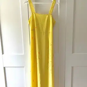 En superfin lång gul klänning som har en slits mitt på baksidan och minimalistisk tryck med blommor.  Klänningen är köpt second hand då jag tyckte den påminde om en relasation par klänning.  Jag säljer den dock då denvar alldelles förstor i bysten för mig
