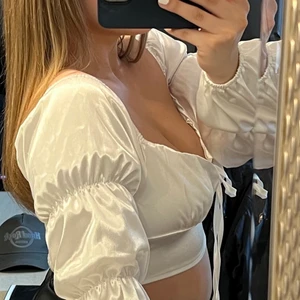 Vit festtop storlek S  - Säljer denna snygga festtoppen i satinimitation. Toppen är inte alls genomskinlig & aldrig använd (nyskick!). Vid intresse, skriv ifall du undrar något eller vill ha fler bilder. 