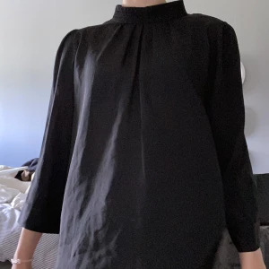 svart blus - en svart blus i tunt material med lite högre hals i storlek 40.   200 kr inklusive leverans 