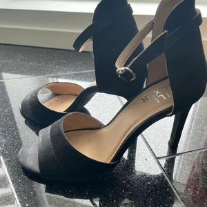 Svarta festskor med klack  - Snygga svarta festskor med klack och öppen tå. Endast använda en gång! 9cm klack.