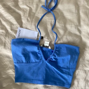 blå topp från monki💙 - en blå topp från monki, väldigt fin färg. knyts i nacken och har öppen rygg. oanvänd, lapparna finns kvar. såå fin till kjolar när man fått lite färg🌞