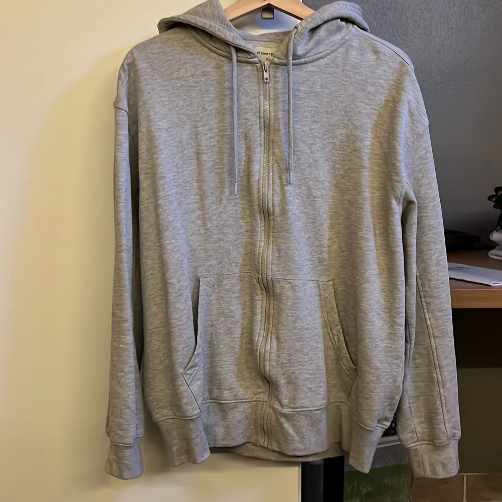 En grå studio total zip hoodie, storlek M/medium. Jag har knappt använt denna tröjan då jag inte riktigt har fått tillfälle. Nypris 499 kr, frakt ingår i priset.. Hoodies.