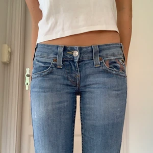 True Religion jeans - Äkta True Religions i jätte bra skick! Slitningen på knät är meningen och de sitter skit snyggt! Jag är 165cm. Inneben: ca 80 cm. Midja: 36 cm rakt över