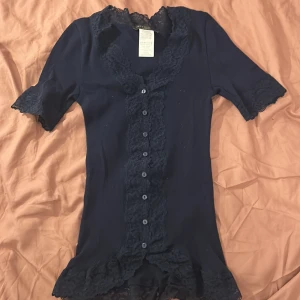 Spetstopp - Aldrig använt marinblå spets-tshirt. Jätte söt och skön. 100% bomull. Säljer på grund av att jag inte gillar spets. Orginalpris: 249kr.