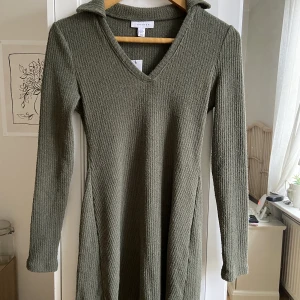 Grön TopShop-Klänning - Aldrig använd, etiketten sitter kvar (se bild). En grön, kortare klänning med långa ärmar. 69% bomull, 28% polyester, 3% elastan. Normal i storleken.