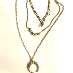 Trio halsband med måne - Ett jätte fint guldfärgat halsband med 3 kedjor. Ena har en måne andra små kulor den tredje en kedja. Nyskick då den aldrig är använd