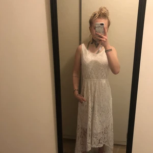 Vit spetsklänning/ examenklänning - Jätte fin vit spets klänning som är längre bak till. Den är använd en gång. Det finns fickor på den på sidorna ganska djupa fickor så man kan ha exempelvis mobilen i.