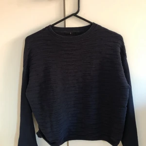Stilren tröja - En fin mörkblå och väldigt stilren långärmad tröja. Tunn och väldigt bekväm från Åhlens, knappt använd men superfin. Den har ett fint mönstrat typ, se bild två. Alltså tyg med lite struktur som skapar ett fint mönster på framsidan