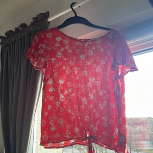 Röd blommig shirt  - Röd blommig t-shirt som jag använt få talls gånger nästan inte alls. Köpte den utomlands därför vet jag inte riktigt vilket märke det är. Inget fel på tröjan alls. Inga fläckar osv. [priset kan dirkuteras]