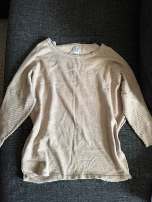 Beige stickad tröja - Mjuk och tunnstickad beige tröja med rund halsringning och avslappnad passform. Tröjan har vida, trekvartsärmar med ribbstickade muddar och en söm längs ryggen som detalj. Perfekt för lager på lager och enkel att styla till olika looks. Skriv privat för fler bilder eller om du har några frågor💗