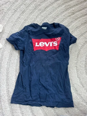 Blå T-shirt från Levis  - Blå T-shirt med logga i fint skick. Storlek: 128/132