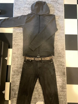 Mörkgrå hoodie med dragkedja - Säljer en stilren mörkgrå hoodie med dragkedja framtill och huva. Hoodien har långa ärmar och två fickor på sidorna. Perfekt för en avslappnad och casual look.  