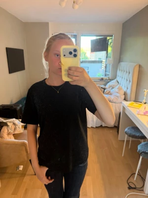 Svart basic t-shirt unisex - En enkel svart t-shirt med rak passform och rund hals. T-shirten är helt utan tryck eller logga och passar perfekt till jeans eller shorts. Materialet ser ut att vara mjukt och bekvämt, troligen bomull eller bomullsblandning.
