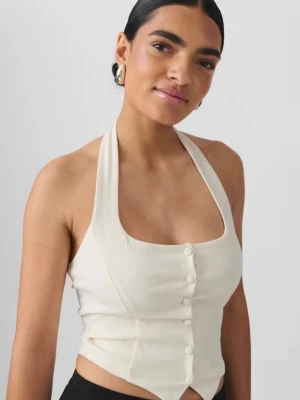Krämvit halterneck väst med knappar - Västen har en figurnära passform och är tillverkad i ett lätt, strukturerat tyg som ger en modern look. Perfekt att styla till både jeans och kjol. Köpt på Gina tricot och använd endast en gång innan jag tyckte att den inte riktigt passade mig, bandet runt halsen är sydd där bak för att den satt väldigt långt ner dock så är den inte klippt så vill man kan man bara klippa upp tråden och använda den som vanligt. Nypris är 300 kr, mitt pris är 99 kr.