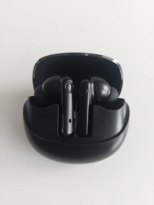 Svarta trådlösa in-ear hörlurar - Snygga svarta trådlösa in-ear hörlurar med laddningsetui. Hörlurarna har en stilren och modern design med rundade former och touchkontroller på sidan. Perfekta för musik, poddar och samtal på språng.