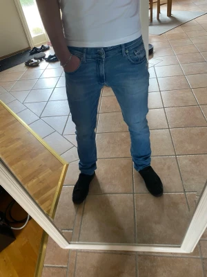 Ljusblå replay slim fit jeans herr - Snygga ljusblå replay jeans med slim fit passform och klassisk femficksdesign. Jeansen har normal midja och är tillverkade i ett stretchigt denimtyg som ger skön komfort och bra rörlighet. Perfekta till en avslappnad stil.