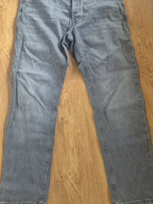 Grå raka jeans - Säljer ett par grå jeans med rak passform och klassisk femficksdesign. Jeansen har normal midja och är tillverkade i ett mjukt denimtyg. Perfekta för en avslappnad och stilren look.