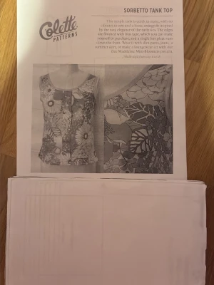 Sy-mönster Colette Sorbetto linnetopp - Säljer ett komplett sy-mönster från Colette Patterns för att skapa en ärmlös linnetopp med blommigt mönster. Mönstret har lös passform, rund halsringning och dekorativ mittveck fram. Passar bäst till lätta material som bomull eller linne. Perfekt för dig som gillar att sy egna kläder. 