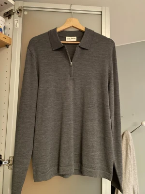 Grå stickad tröja med krage  - Stilren grå långärmad tröja från Enkel Studio med klassisk krage och halv dragkedja framtill. Tillverkad i ett mjukt, tunt stickat material som ger en clean look. Perfekt till jeans eller chinos för en avslappnad men snygg outfit. Hör gärna av er om ni har några frågor eller funderingar! 
