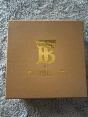 Burberry bälte med klassiskt rutmönster - Snyggt Burberry-bälte med det ikoniska beige, röda och svarta rutmönstret. Bältet har ett stort guldfärgat B-spänne och är gjort i skinn. Perfekt accessoar för att lyfta din outfit. Boxen och allt annat ingår. Pris kan diskuteras i DM. 