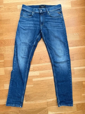 Blå jeans från Replay - Snygga blå slim fit jeans från Replay med klassisk femficksdesign och dragkedjegylf. Jeansen har en lätt tvättad look med subtila slitningar och är tillverkade i mjukt denimtyg som ger en skön passform. Perfekta till en avslappnad stil. Storlek 14Y model Wallys, hör gärna av er vid funderingar😁