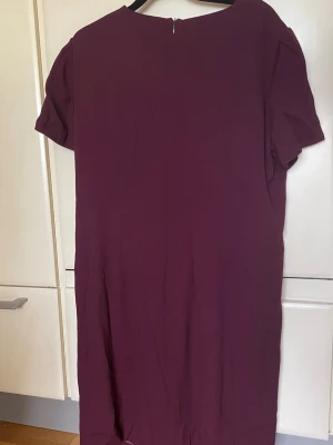 Gant klänning vinröd stl 42 - Säljer en vinröd klänning från GANT i enkel och stilren design. Klänningen har korta ärmar, rund halsringning och dragkedja i ryggen. Passformen är normal och tyget känns mjukt och följsamt. Perfekt för dig som gillar klassiska plagg med modern touch.