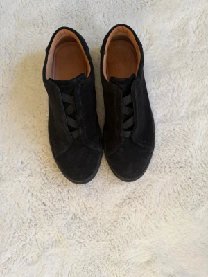 Svarta mockasneakers myrqvist  - Stilrena svarta sneakers i mocka med resårband istället för klassiska skosnören. Låg modell med svart yttersula och beige insida. Perfekta för dig som gillar minimalistisk och clean stil. Passar till det mesta och är enkla att ta på. Köpta för 2500. Skonsamt avnända.